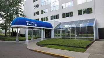 Un edificio moderno con un acceso cubierto identificado como 'Sal's' y una zona con cerramientos de vidrio.