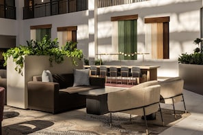 A modern outdoor seating area with a sofa, chairs, and a table, surrounded by potted plants and a patterned rug. - Embassy Suites by Hilton Cincinnati Northeast Blue Ash (Cincinnati)