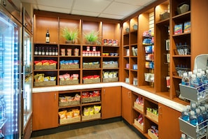 Un supermercado ordenado con diversos productos alimenticios, aperitivos y bebidas en los estantes.