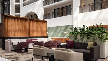 Een modern buitenzitgedeelte met een combinatie van banken en stoelen, een houten scheiding en een groene betegelde muur.