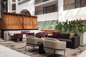 A modern outdoor seating area with a mix of sofas and chairs, a wooden partition, and a green tiled wall. - Embassy Suites by Hilton Cincinnati Northeast Blue Ash (Cincinnati)