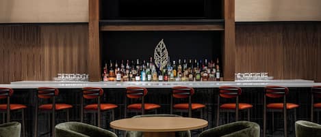 A bar area with a long counter, multiple stools, and a round table.
