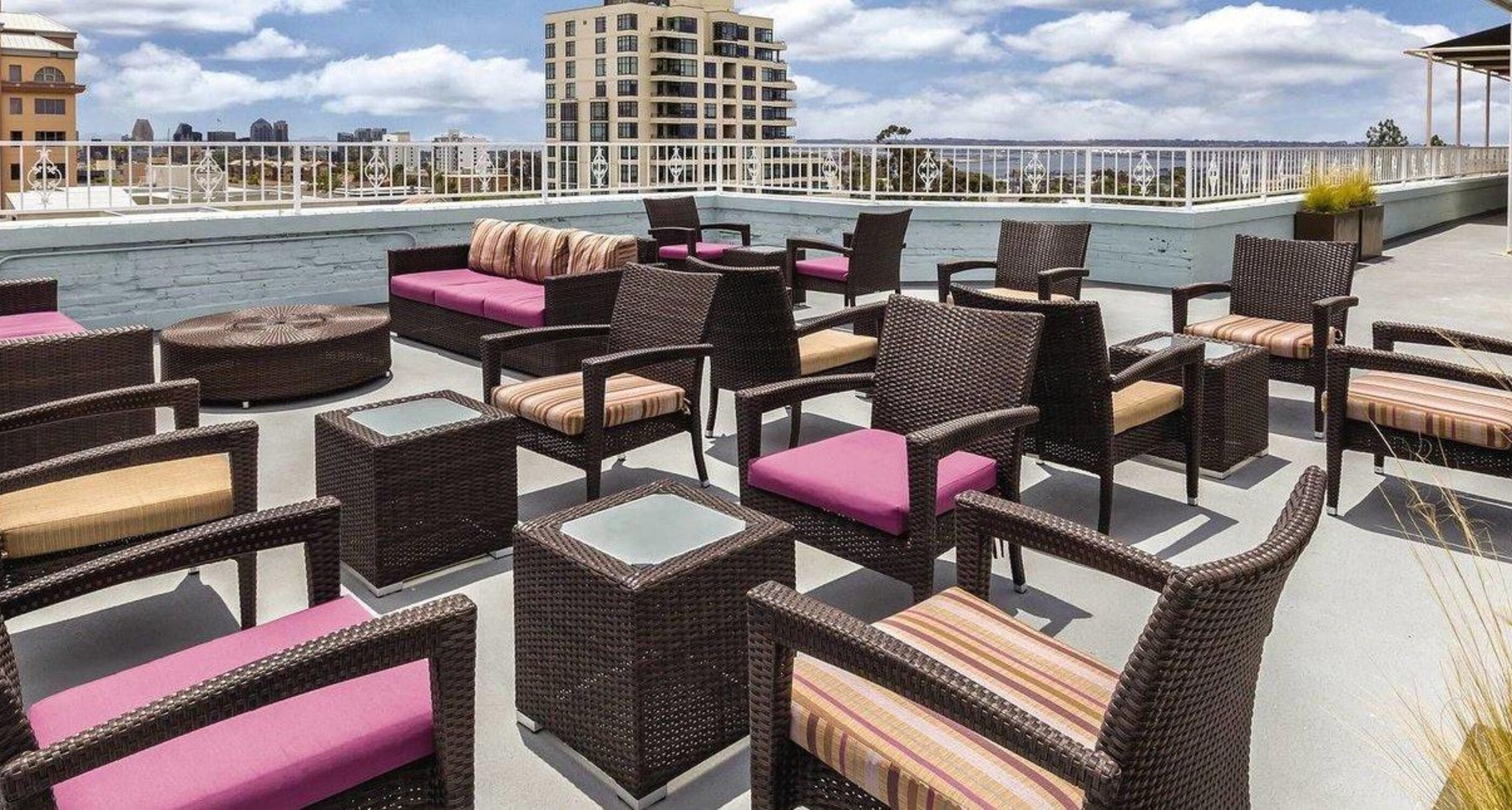 Une terrasse sur le toit, aménagée avec des meubles en osier et des coussins, offrant une vue sur le paysage urbain.
