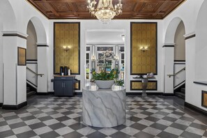 A lobby with a marble column, a chandelier, and a checkered floor. - Inn At The Park (San Diego)