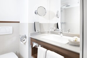 A modern bathroom with a white sink, a large mirror, a towel rack, and a shower. - Fora Hotel Hannover by Mercure (Hannover)