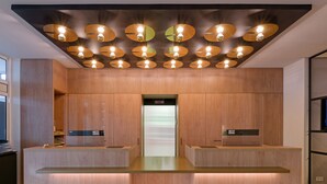 A reception area with wooden paneling, a central counter, and multiple ceiling lights. - Fora Hotel Hannover by Mercure (Hannover)