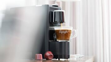 A coffee machine dispensing coffee into a cup with the brand name visible.