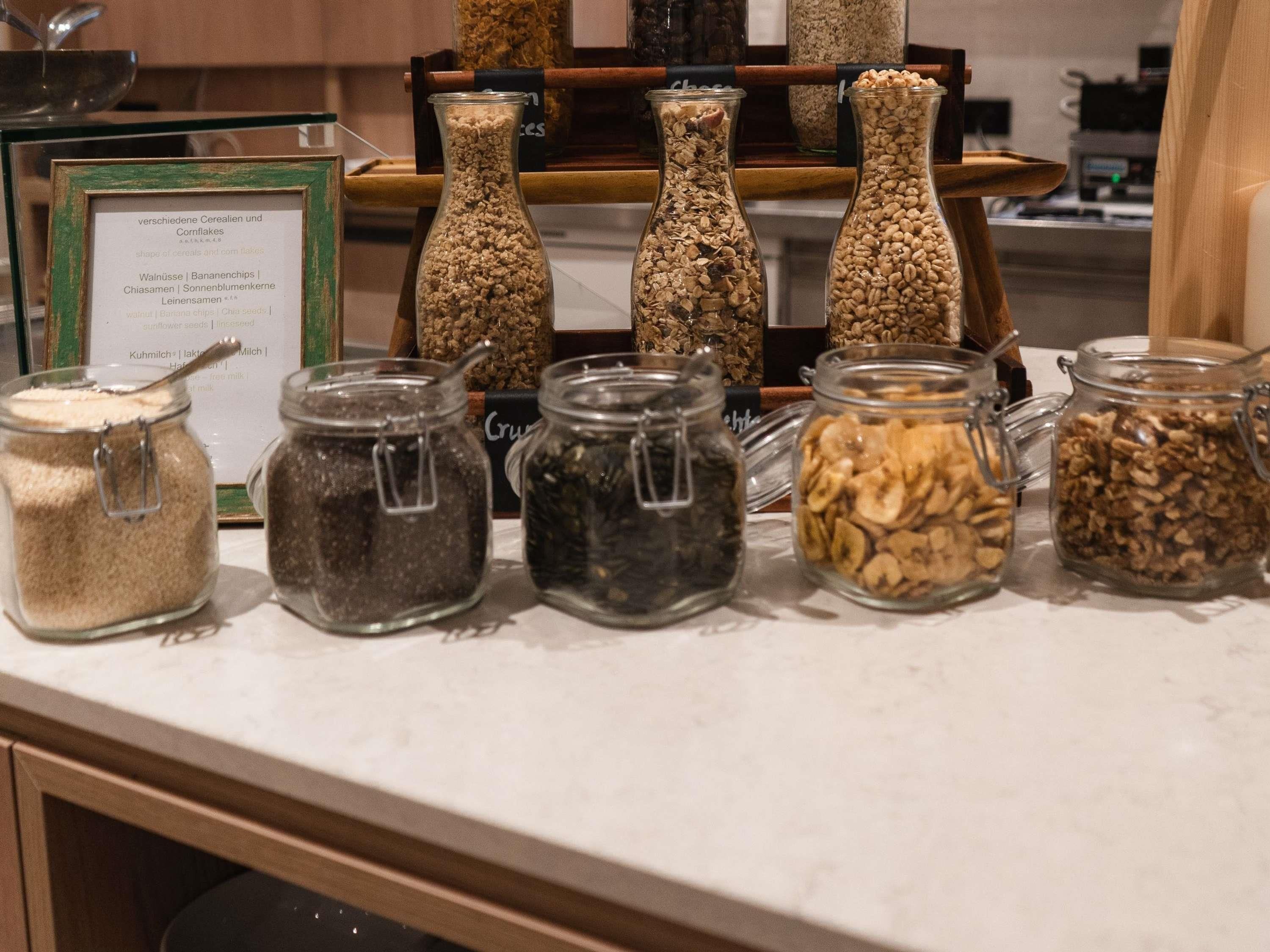A variety of grains and seeds in glass jars on a countertop.