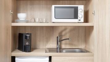 Una cocina compacta equipada con microondas, cafetera y pileta.