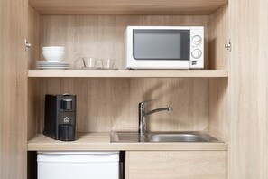 A compact kitchen with a microwave, coffee maker, and sink.