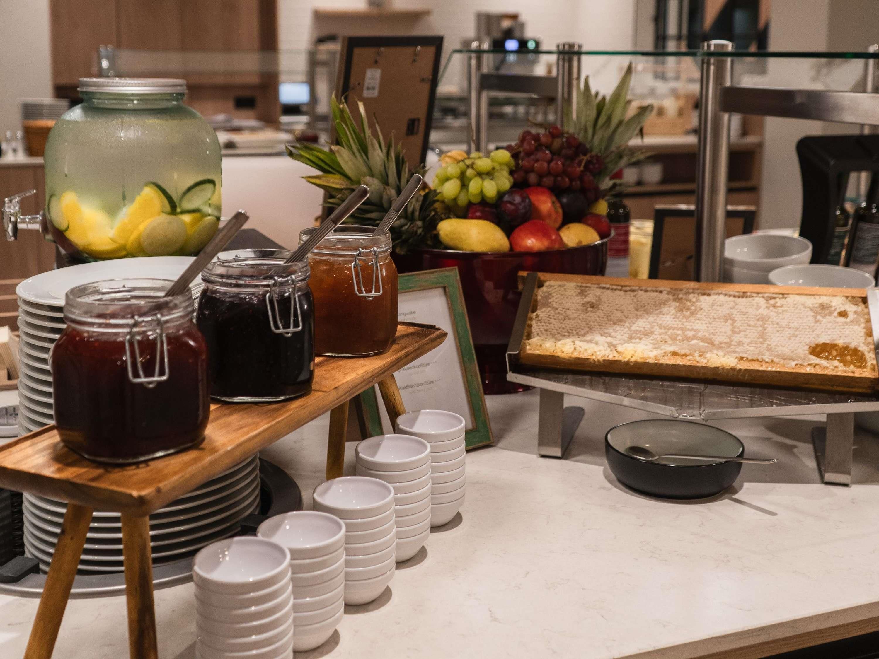 A buffet setup with various food items, including fruits, condiments, and a dessert tray.