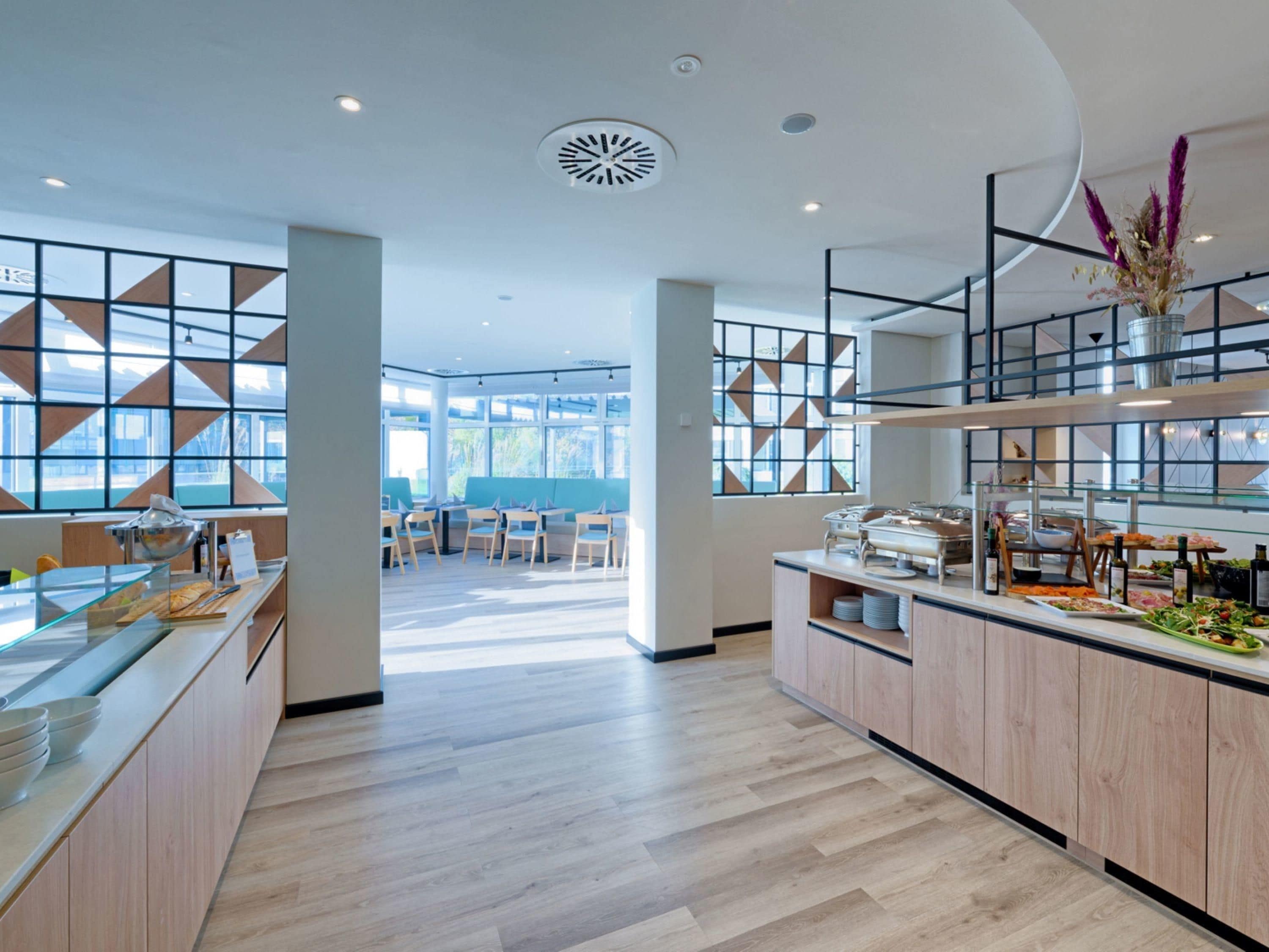 Eine moderne Hotelhalle mit einer zentralen Bar, Sitzgelegenheiten und großen Fenstern.