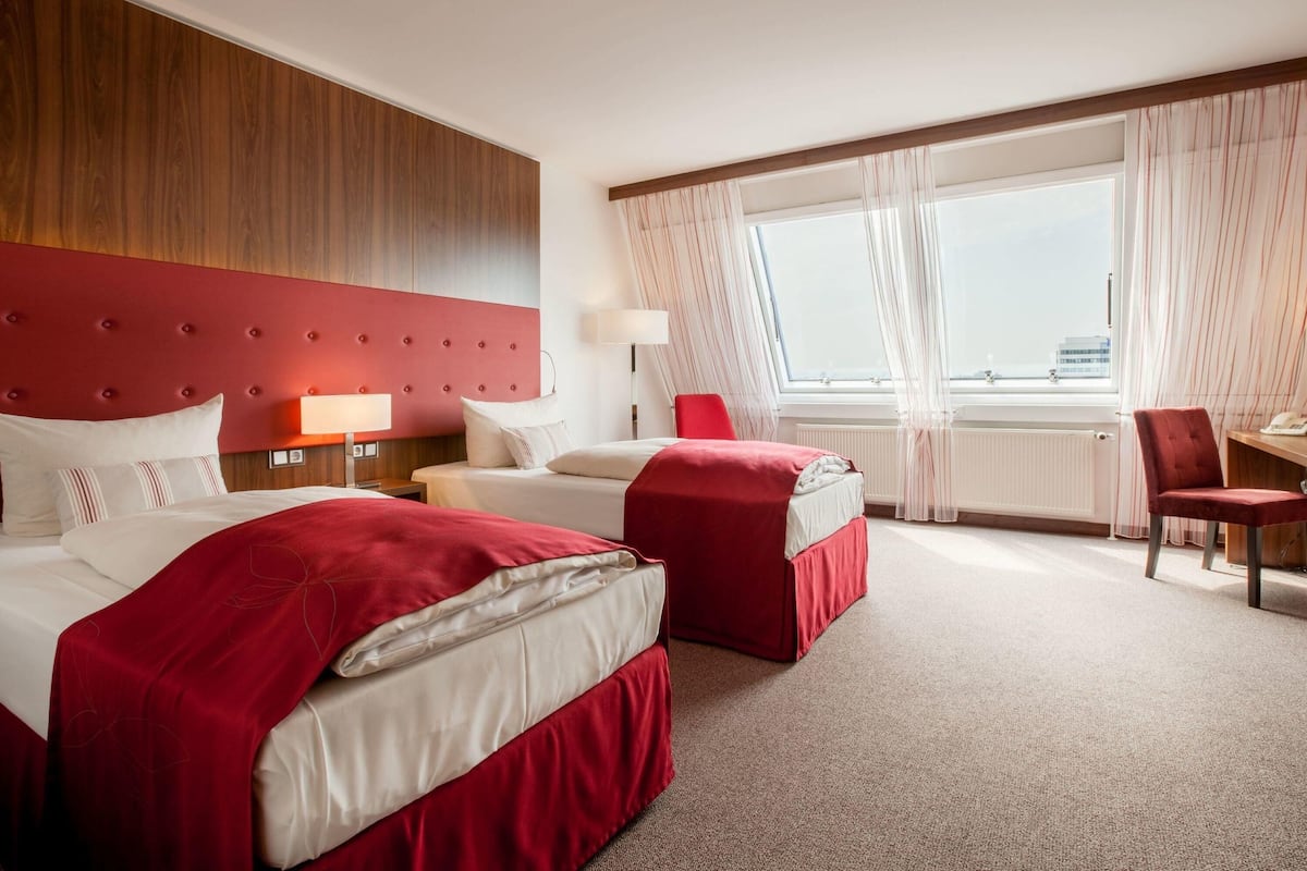 A hotel room with a large bed, a smaller bed, a desk, and a chair.