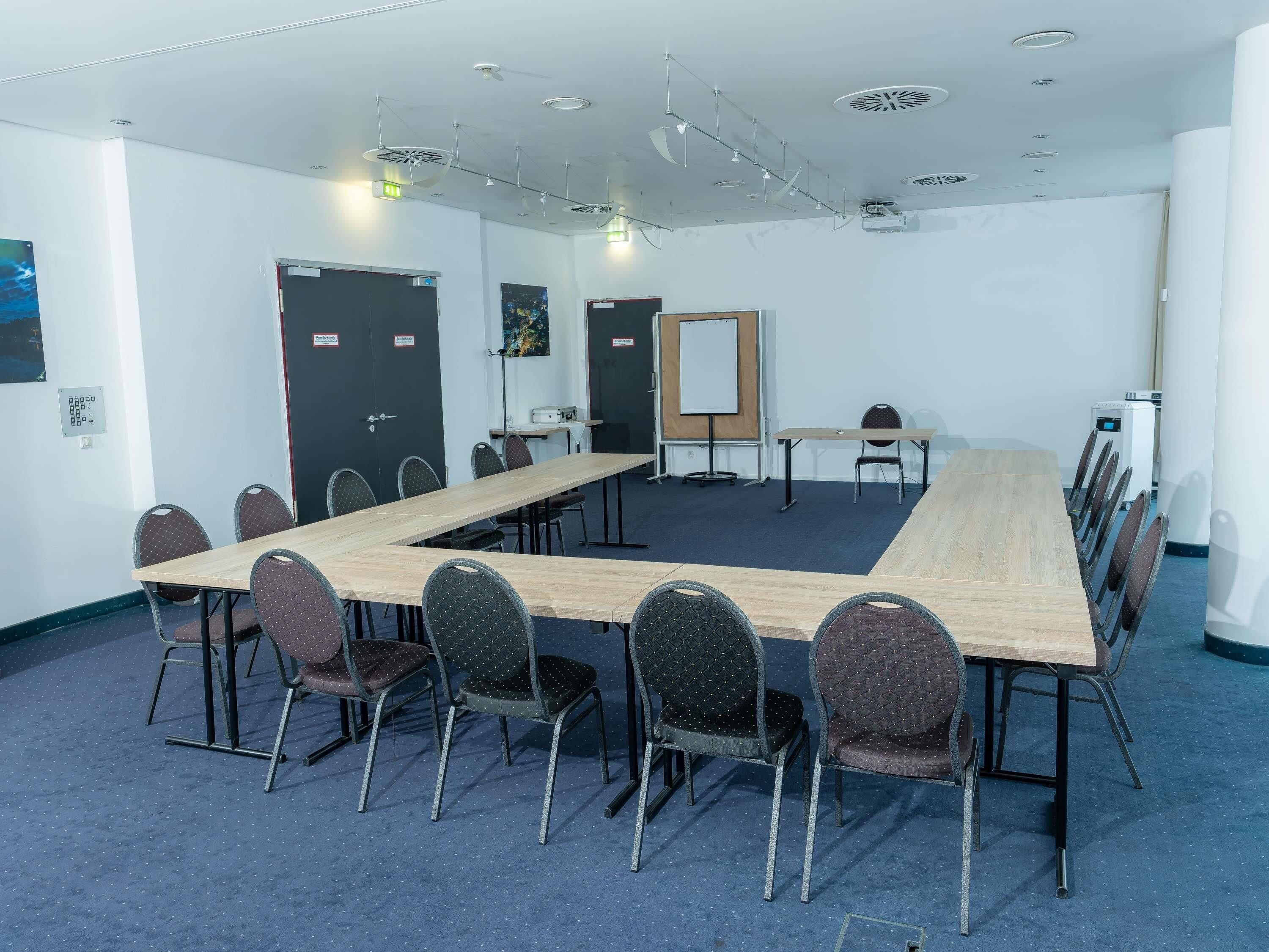A conference room with a long table, chairs, a whiteboard, and a projector.