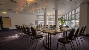 A conference room with a long table, chairs, and a projector screen. - Fora Hotel Hannover by Mercure (Hannover)