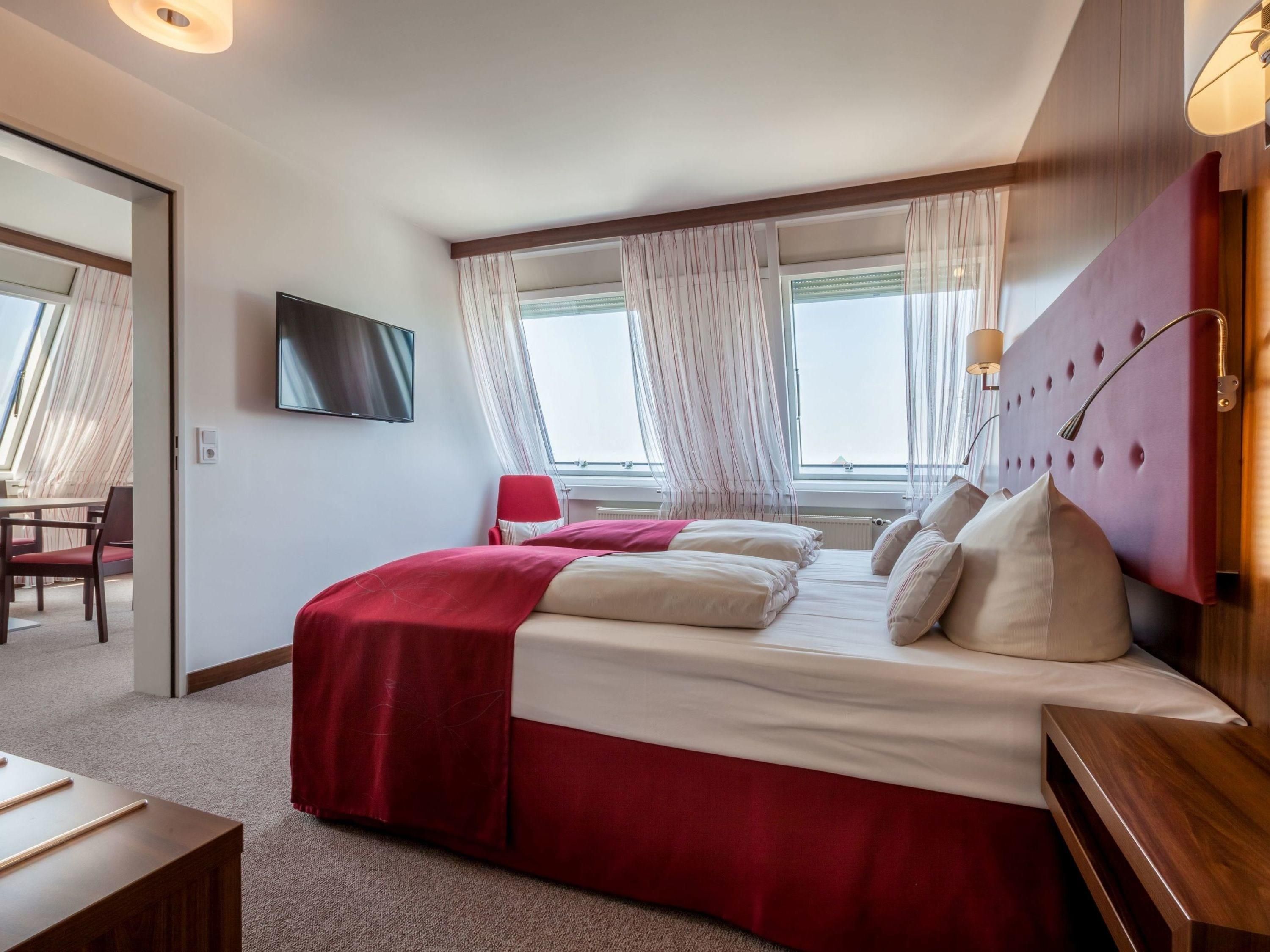 Ein Hotelzimmer mit Bett, Fernseher, Schreibtisch und Stuhl.