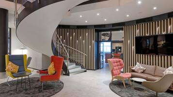 A modern interior with a curved staircase, a sofa, a chair, and a TV.