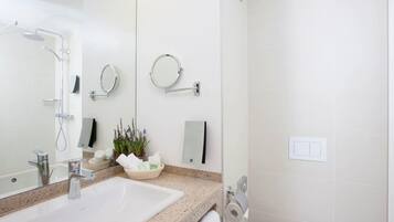 Un baño moderno con lavamanos, espejo, toallero y ducha.