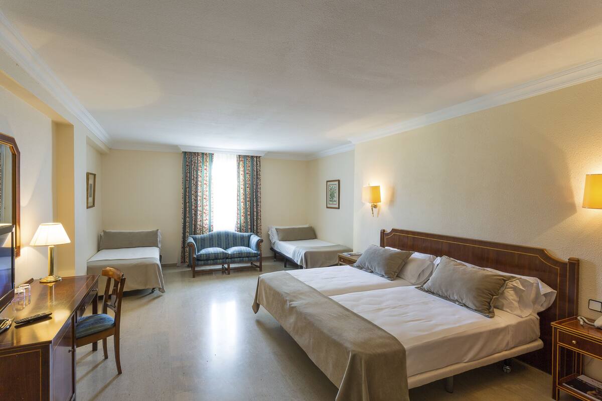Een hotelkamer met twee bedden, een bureau met lamp, een stoel en een televisie.