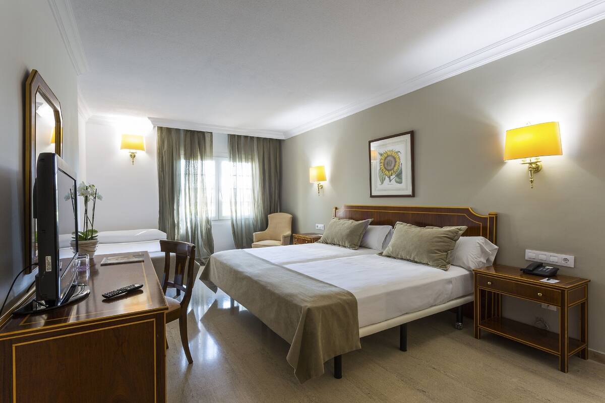 Een hotelkamer met een groot bed, nachtkastjes, een bureau met een computer en een televisie.