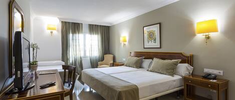 A hotel room with a large bed, bedside tables, a desk with a computer, and a TV.