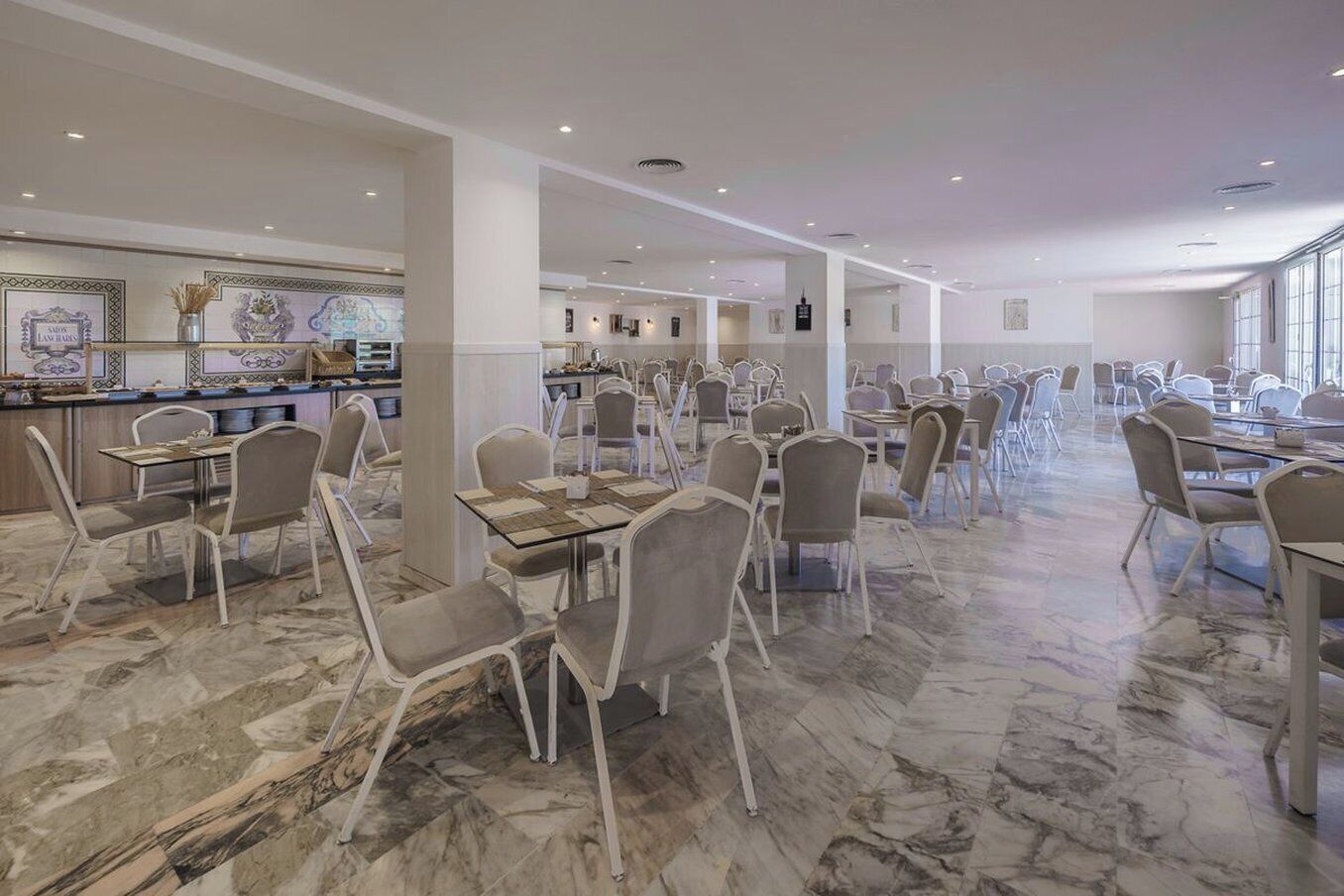 A spacious dining area with marble flooring and modern chairs, featuring a bar area with decorative elements.