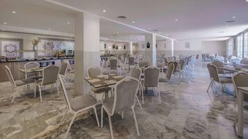 A spacious dining area with marble flooring and modern chairs, featuring a bar area with decorative elements.