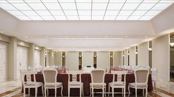 A conference room with a long table, white chairs, and a high ceiling with skylights.