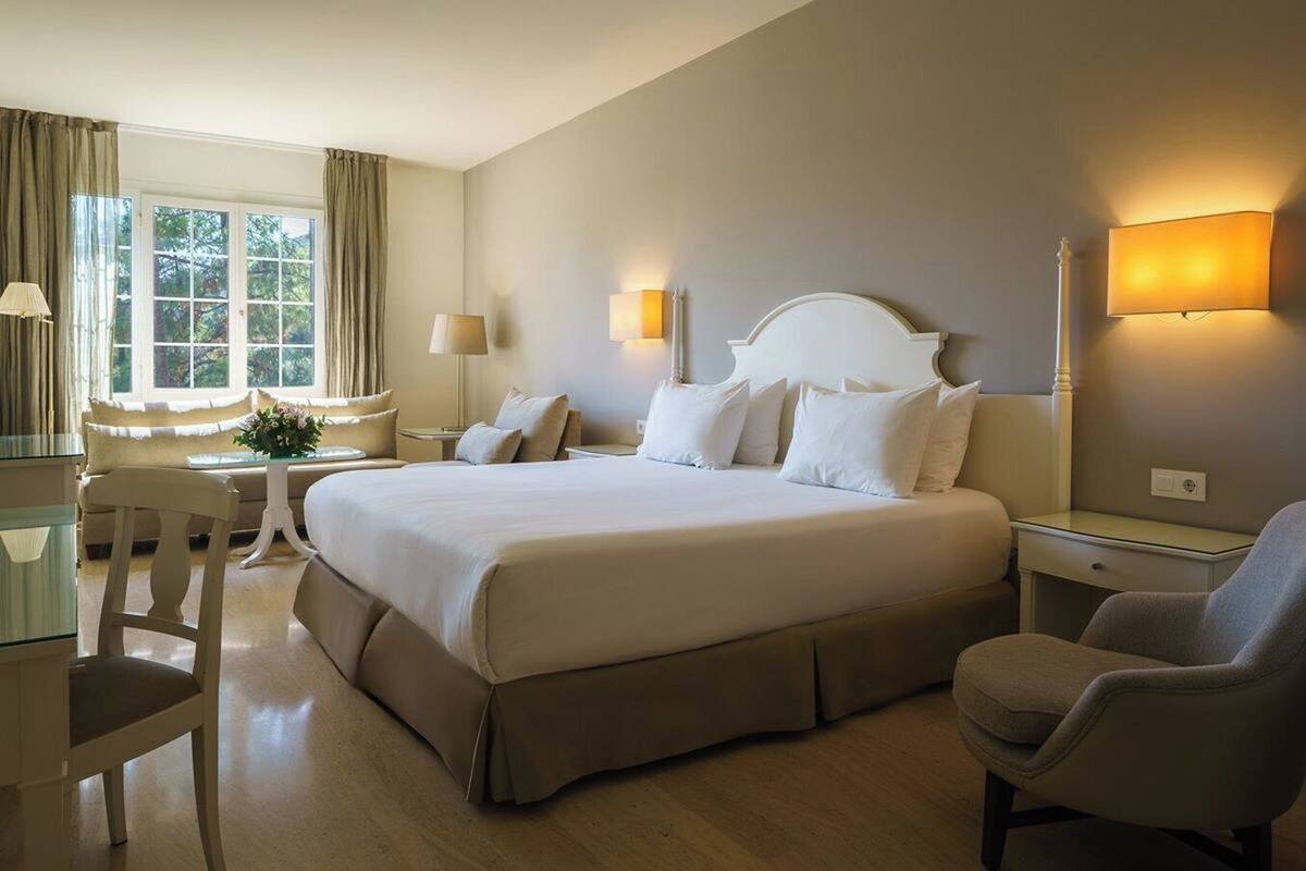 Een hotelkamer met een groot bed, een bureau, een stoel en een raam met gordijnen.