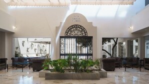 Un vestíbulo amplio con techo alto, una reja decorativa central y zonas de estar.