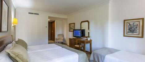 A hotel room with two beds, a desk with a computer, a chair, and a television.