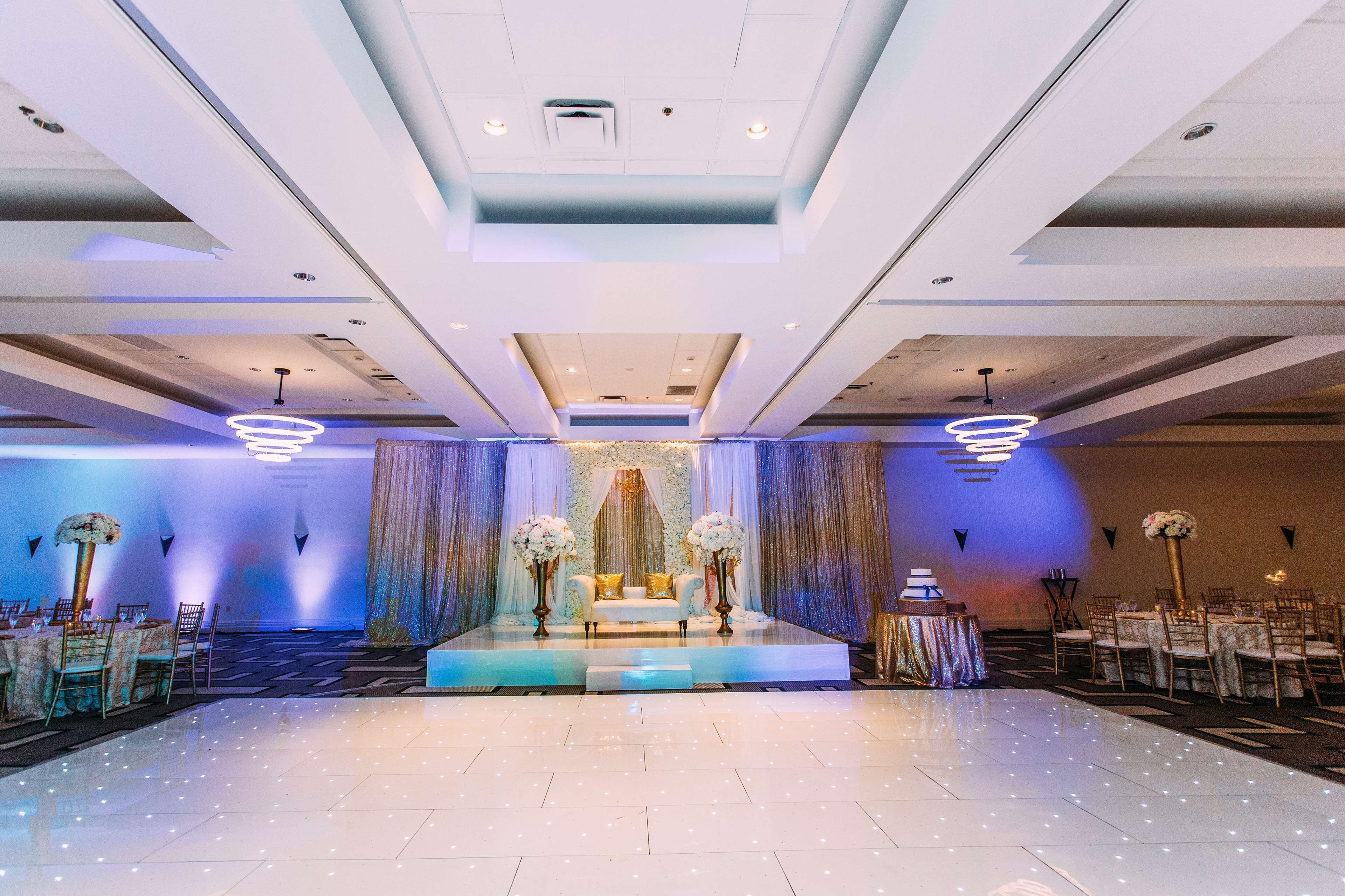 A spacious hall with a stage, tables, and chairs arranged for an event.
