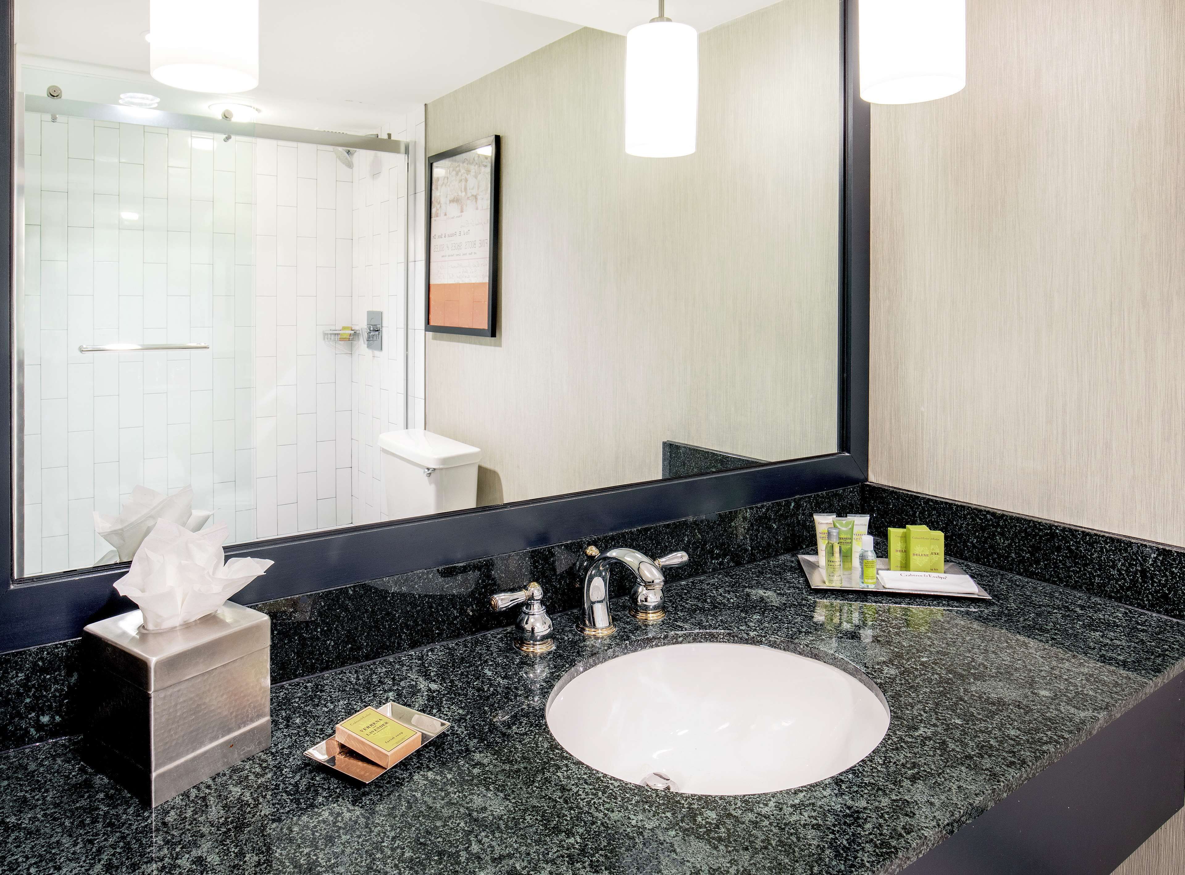 A modern bathroom with a black granite countertop, a white sink, and a large mirror.