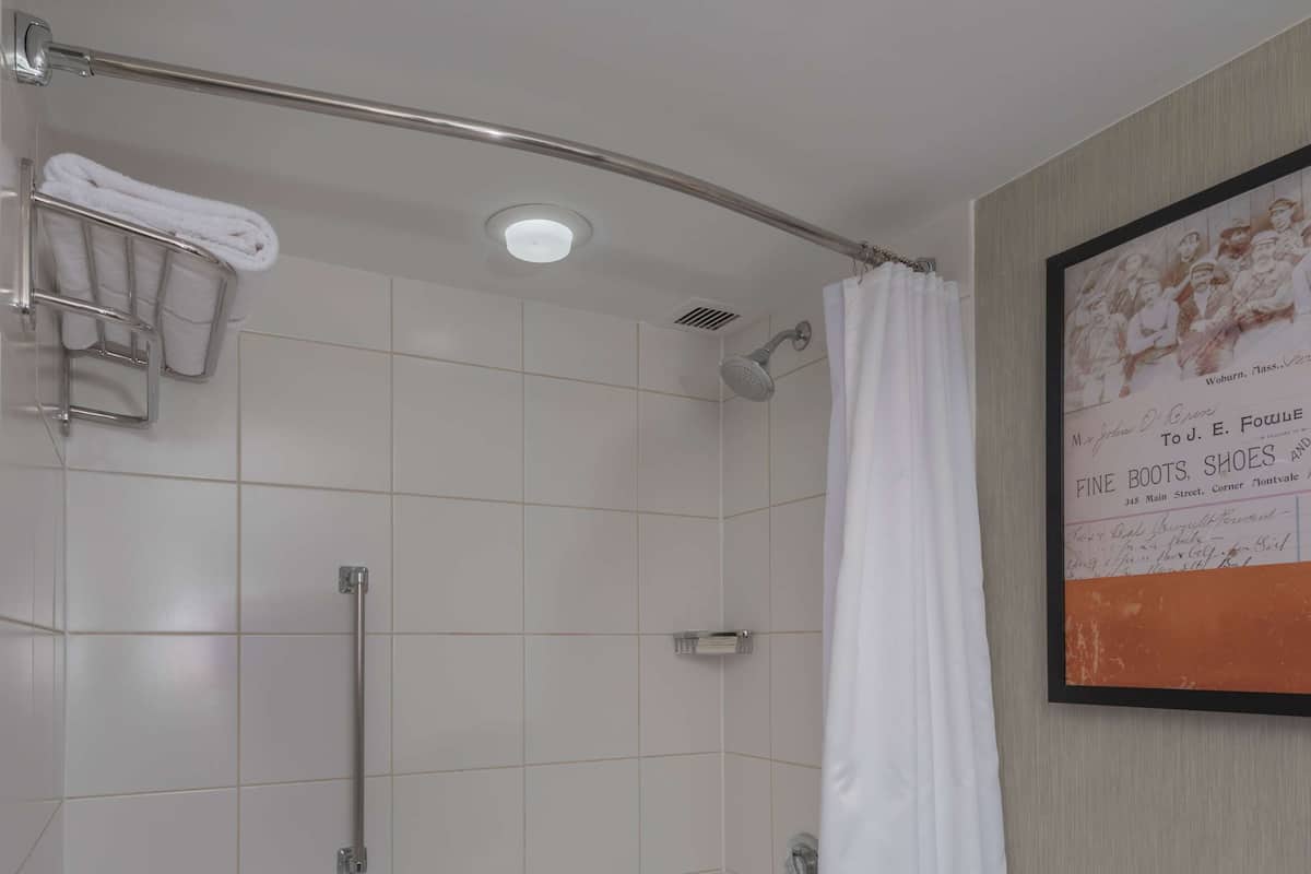 A bathroom with a bathtub, toilet, and shower area.