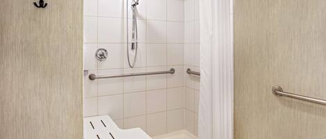 A modern bathroom with a shower, grab bars, and a white sink.