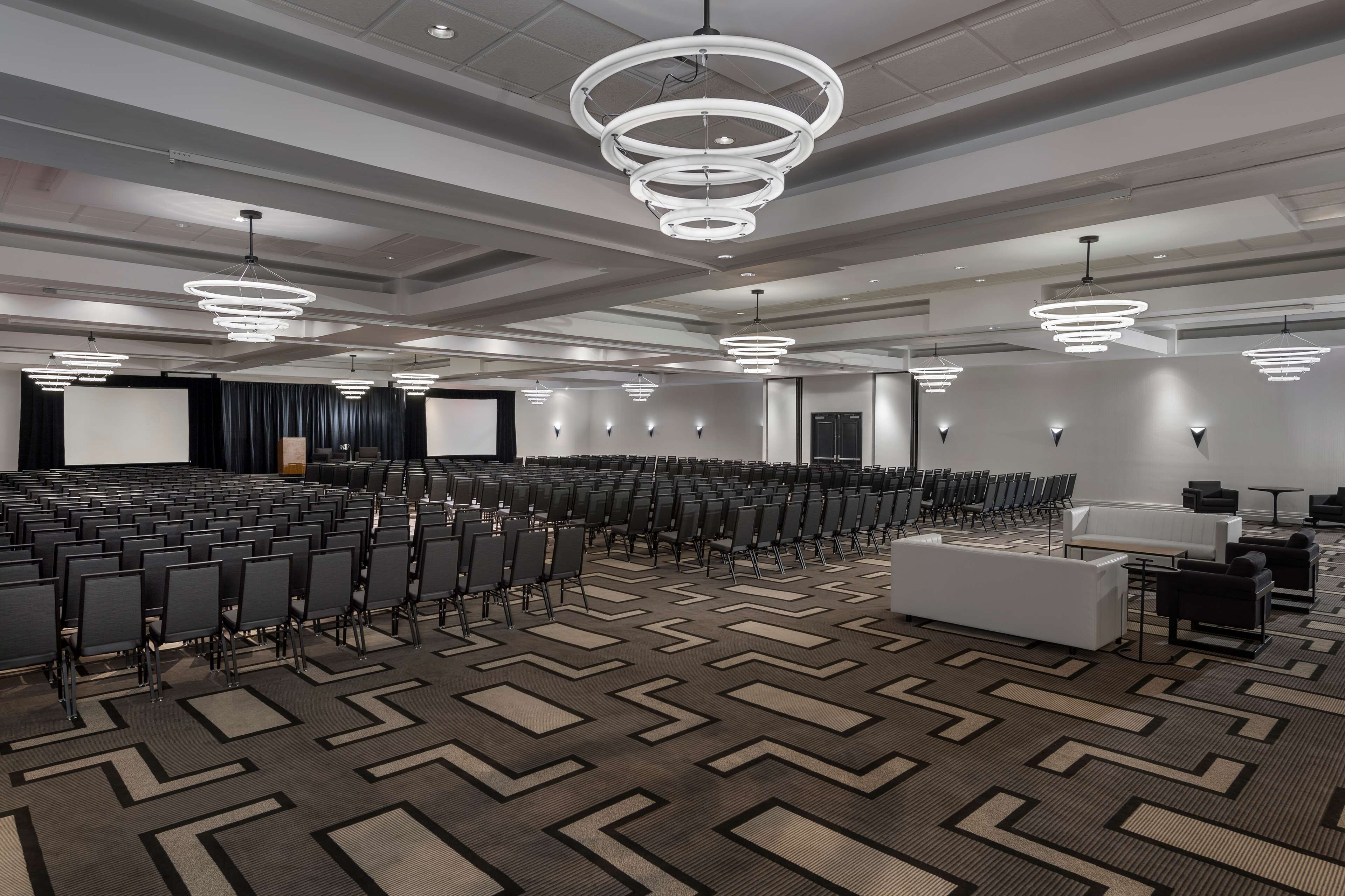 A large conference room with rows of chairs, a stage, and modern lighting fixtures.