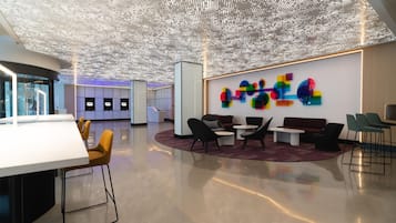 A modern lobby with a ceiling of illuminated dots, seating areas, and a wall with colorful geometric shapes.