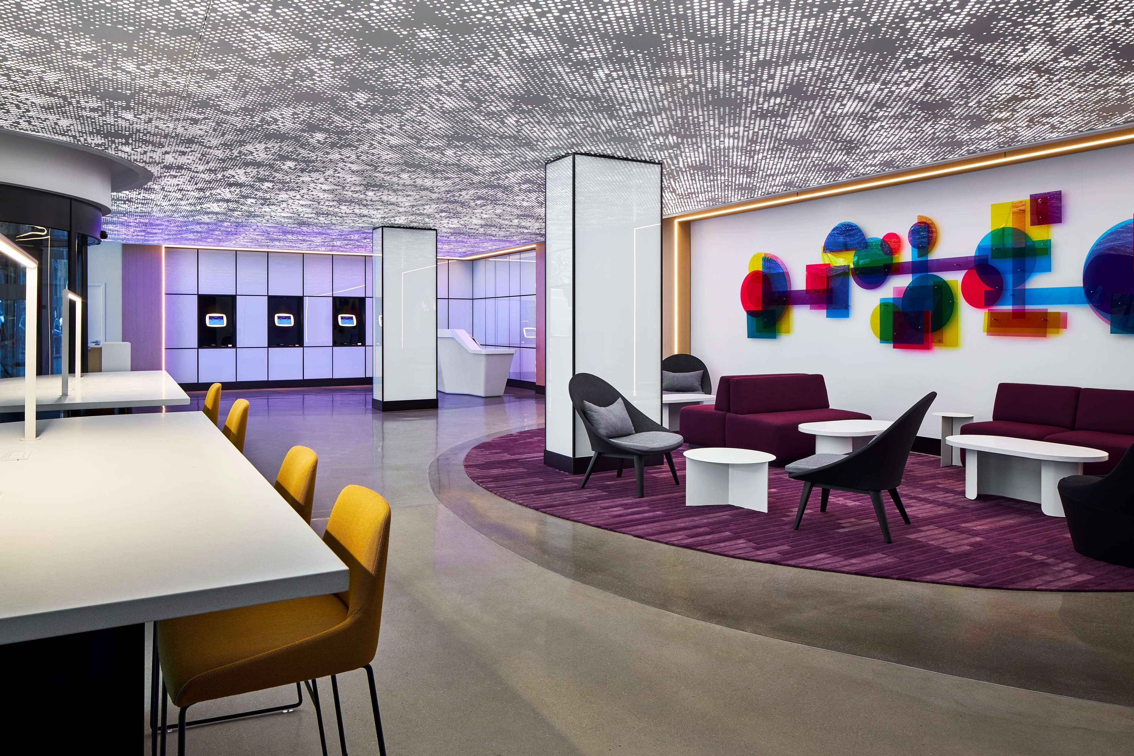 Un interior moderno con mostrador de recepción, zona de estar y una obra de arte abstracta y colorida.