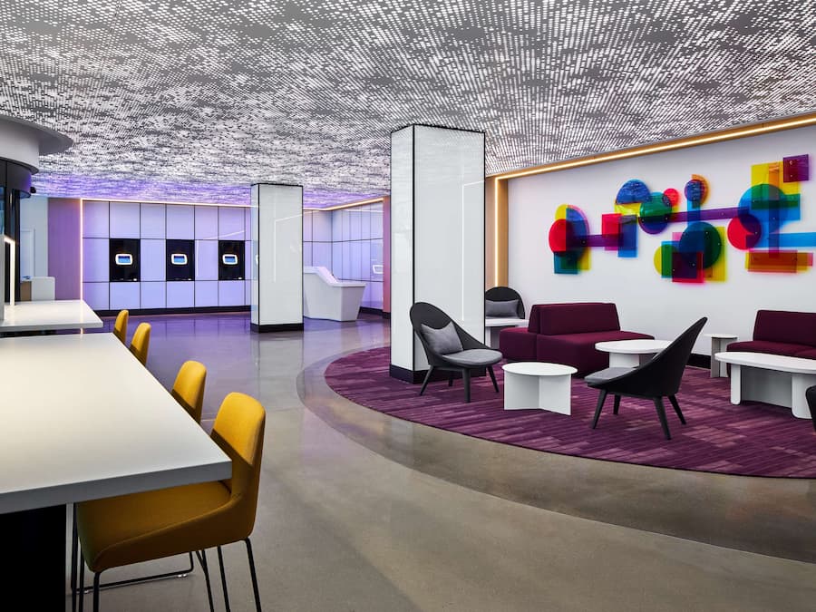 Un interior moderno con mostrador de recepción, zona de estar y una obra de arte abstracta y colorida.