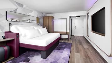 A modern bedroom with a bed, bedside table, TV, wardrobe, and a mirror.