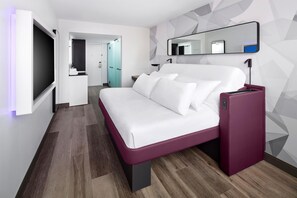 A modern hotel room with a bed, a TV, a mirror, and a minibar. - YOTEL Washington DC, Select by Hilton (Washington)