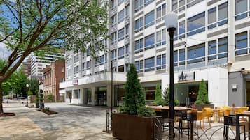 A hotel with a modern facade, outdoor seating area, and a clear sky.