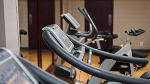 Un gimnasio con equipo de ejercicio, incluyendo cintas de correr y bicicletas estáticas.
