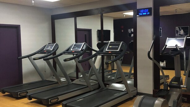 Ett gym med löpband, en motionscykel och en vägg full med speglar.