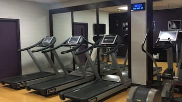 Une salle de sport équipée de tapis de course, d’un vélo d’appartement et d’un mur entièrement recouvert de miroirs.