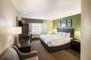 Habitación de hotel con cama, escritorio, silla y una pequeña mesa.