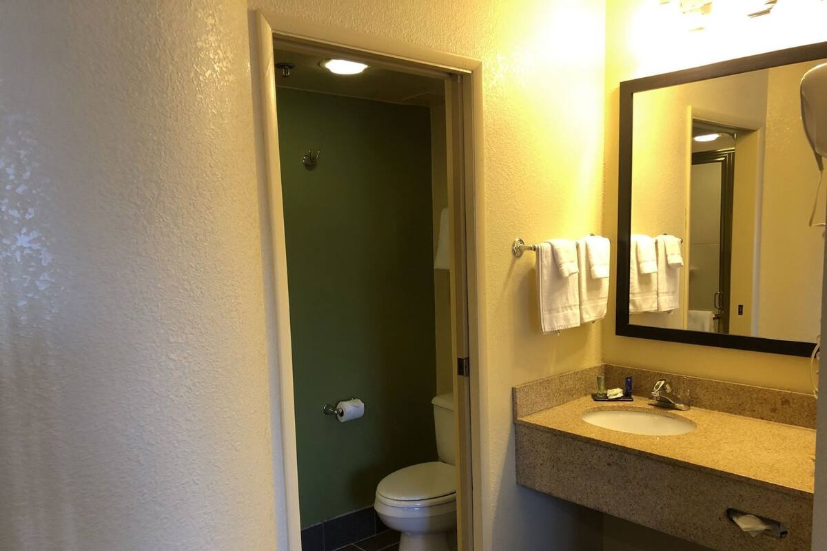 Ein Badezimmer mit Toilette, Waschbecken, Spiegel und Handtuchhalter.