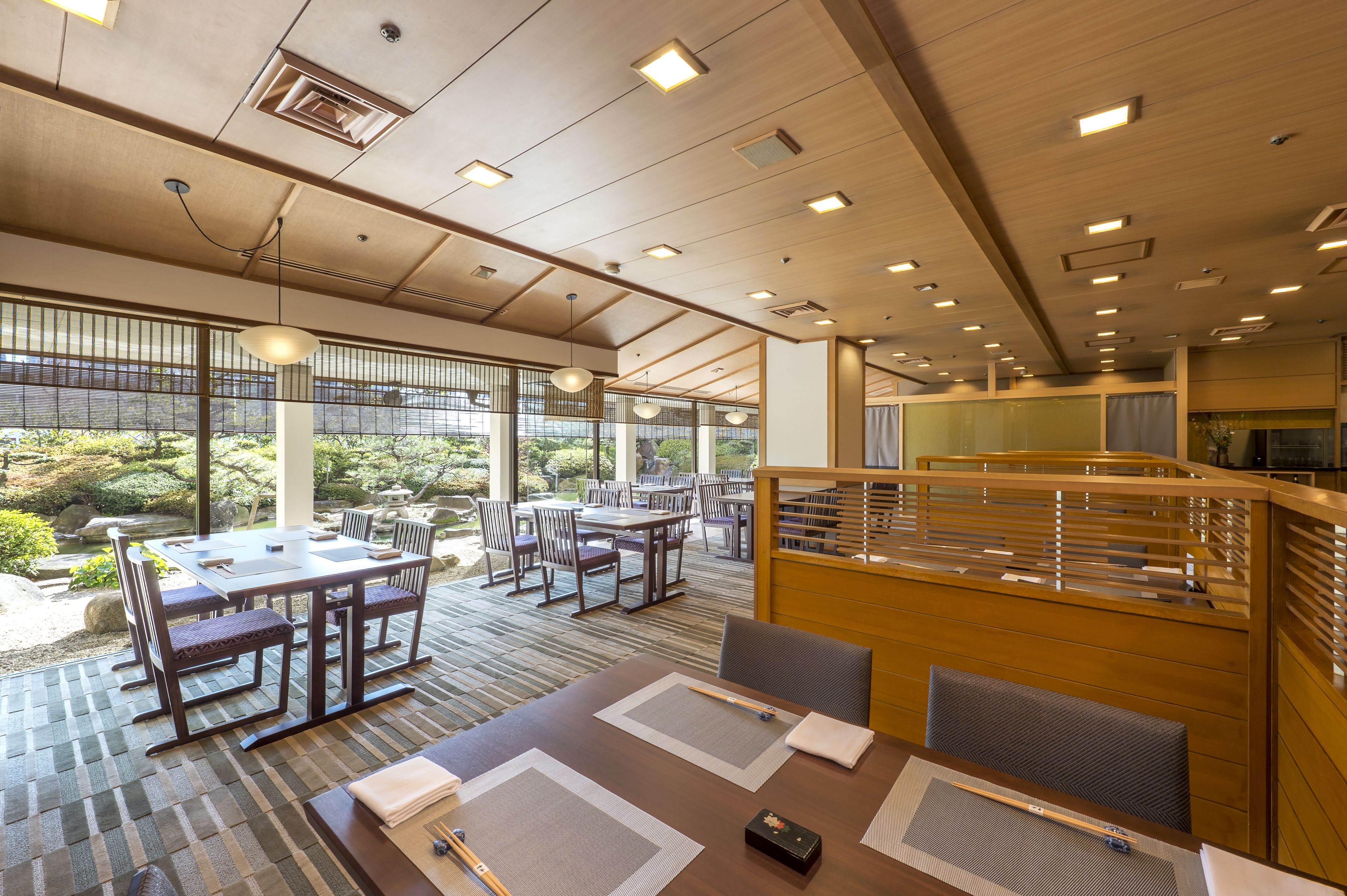 A modern dining area with tables and chairs, large windows, and a view of the outdoors.
