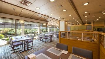 A modern dining area with tables and chairs, large windows, and a view of the outdoors.
