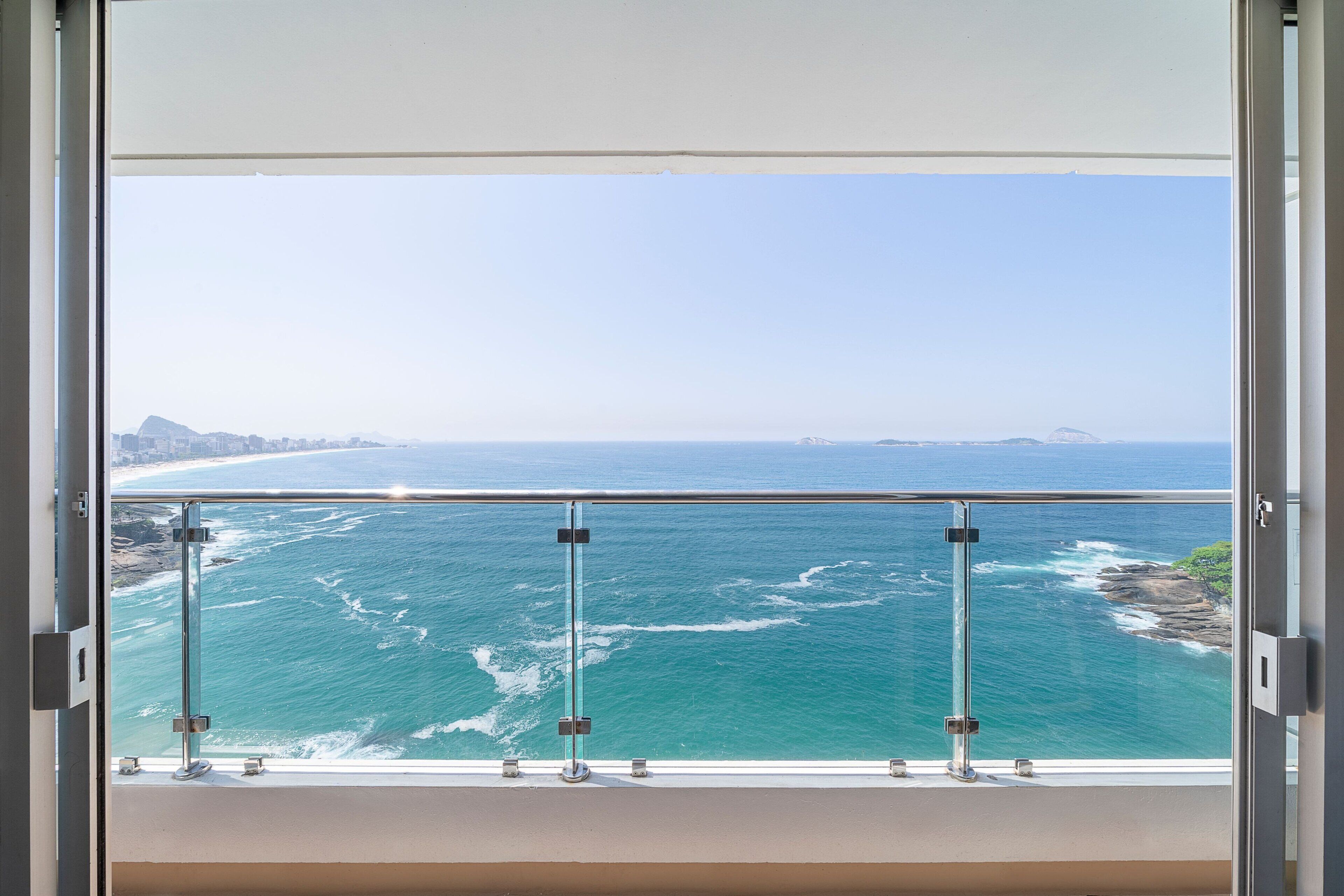 A balcony with a glass railing overlooking a coastal view.